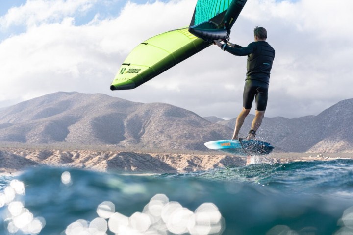 a man holding a kite while standing in a body of water